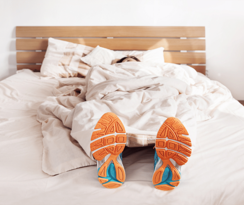 Image of an athlete sleeping with running shoes on in bed
